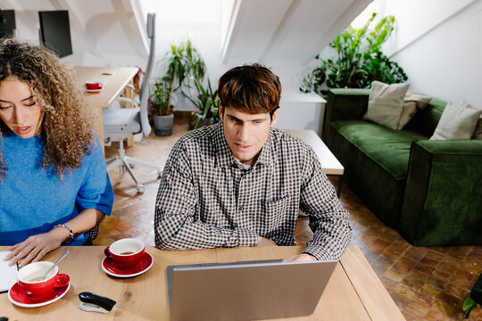 Freelancer using a laptop to complete work tasks alongside his partner