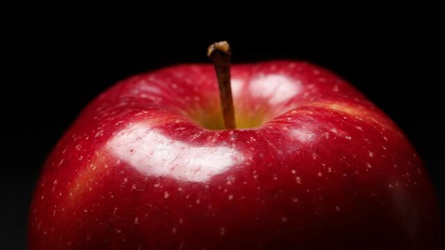 Close up of a shiny red apple with water droplets.