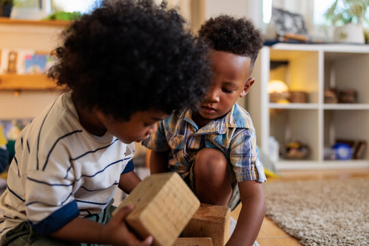 Two young boys playing with wooden blocks indoors.