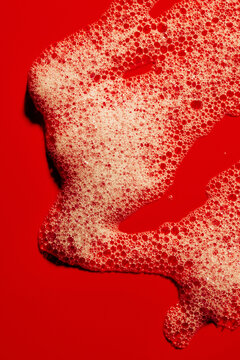 Bubbles Form Patterns on a Red Surface With Varied Shapes and Sizes