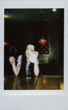 A woman cries with a glass of wine in her hand, wiping away her tears