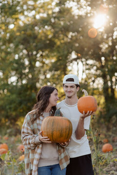 A brother and sister having fun searching for a pumpkin at a pumpkin patch in October.