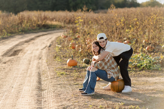 A brother and sister having fun searching for a pumpkin at a pumpkin patch in October.
