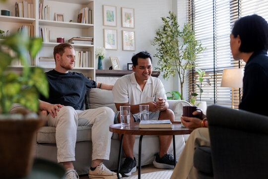 Three people conversing in a bright, modern living room.