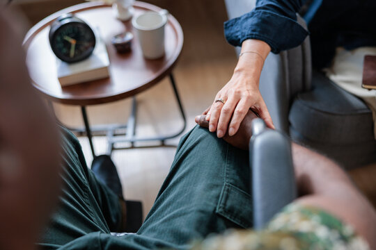 Hand rests on another's knee in a comforting gesture.