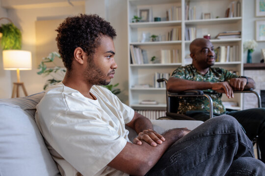 Two men in a living room, one in wheelchair.