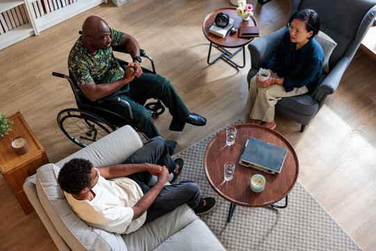 Three people in a living room, conversing.