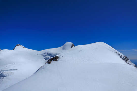 Mountain glacier panorama of Monte Rosa massif with summits Zumsteinspitze, Signalkuppe with mountain hut Margherita Hut and Parrotspitze (left to right) in Pennine Alps, Italy and Switzerland