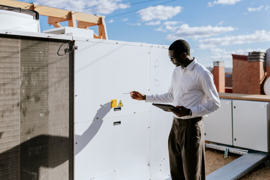 Engineer inspecting rooftop HVAC equipment on sunny day