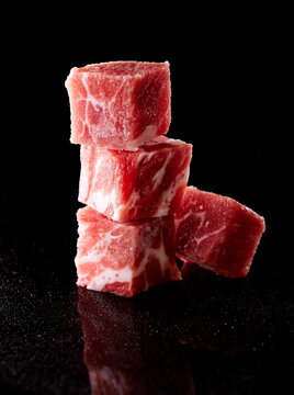 Closeup of beef cubes stacked on black background