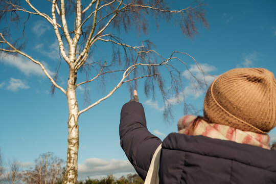 Woman Pointing at Bare Winter Tree