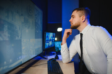 Security guard monitoring surveillance cameras in control room