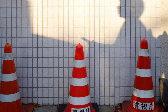 Morning shadows of people hurrying to work cast over striped cones