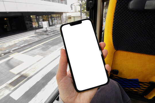 Hand Holding a Smartphone with Blank Screen Sitting by Bus Window.