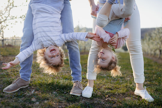 Parents lifting children upside down during playful springtime moment.