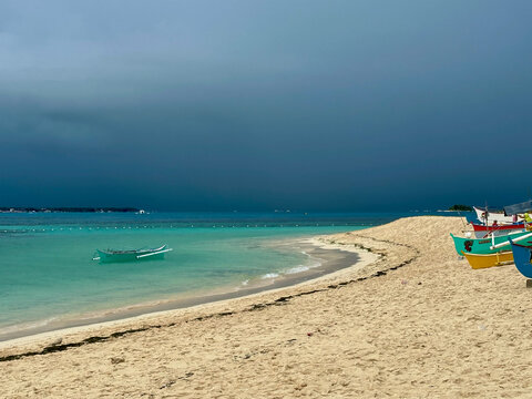 Storm over tropical sea with boats on island with turquoise waters, Guyam Island, Siargao, Philippines 