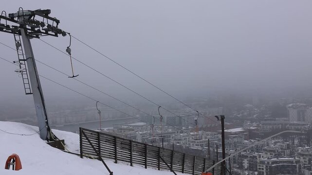A slow‑motion shot of an empty ski lift lift gliding past the camera on a snowy slope in Hammarbybacken Stockholm Sweden. No riders present. Filmed February 26 2026. One of the last days with snow.  