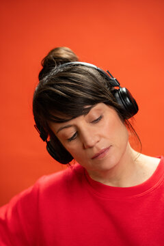 Woman in red sweatshirt listening to music with headphones
