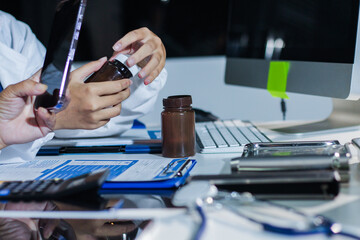 Fototapeta premium Medical team having a meeting with doctors in white lab coats and surgical scrubs seated at a table discussing a patients working online using computers in the medical industry.