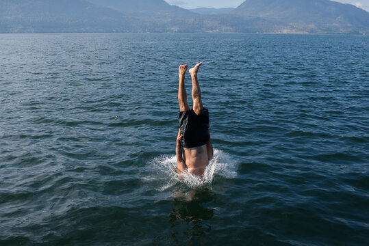 Person Diving Head First Lake From Standing Position in Sunny Weather