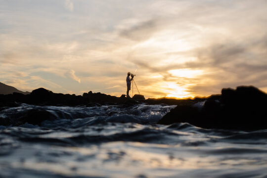 Seascape with the silhouette of a videographer capturing the sunset