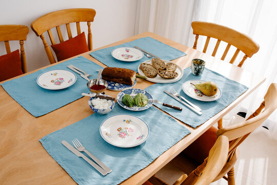 Breakfast table arranged with fresh fruit, slices of bread and avocado