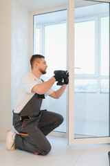 Man installing new plastic window frame using power drill