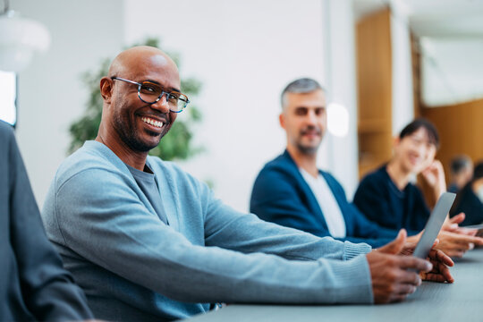 Smiling Man At Desk During Team Meeting
