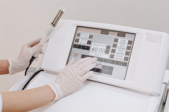 Esthetician adjusting a professional facial treatment device touchscreen in a medical spa setting