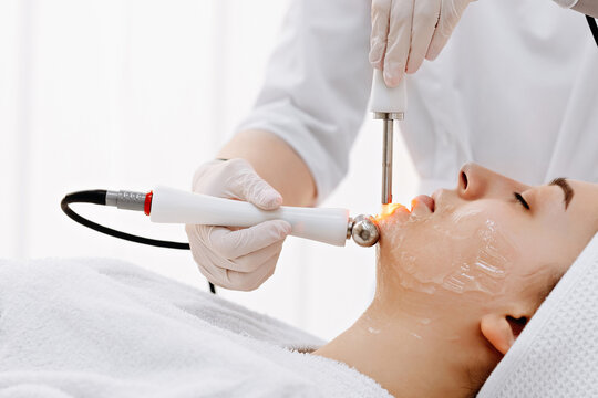Woman receiving professional laser and radiofrequency facial treatment at a medical spa for skin rejuvenation