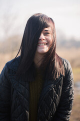 Fototapeta premium Smiling woman with windblown hair in warm sunlight