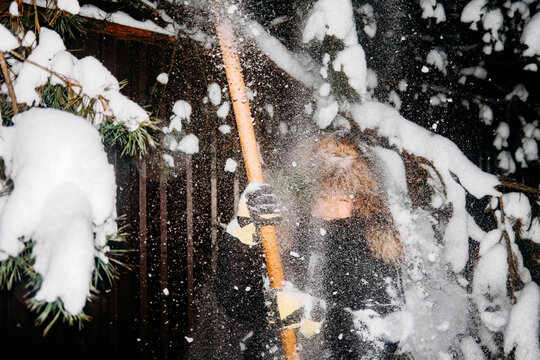 Person removes snow from tree branches at night