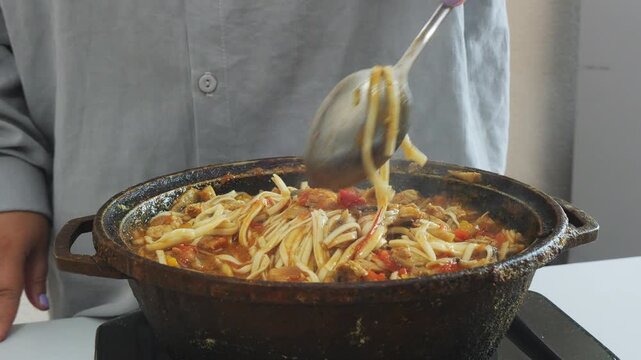 Vegetables with chicken and udon simmer in a cast iron skillet