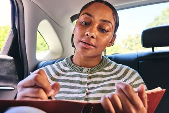 Young woman making notes in a car 