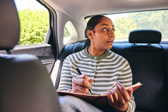 Young woman making notes in a car 