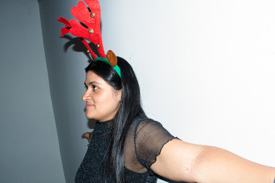 Woman Wears Reindeer Antlers While Standing Against a Wall