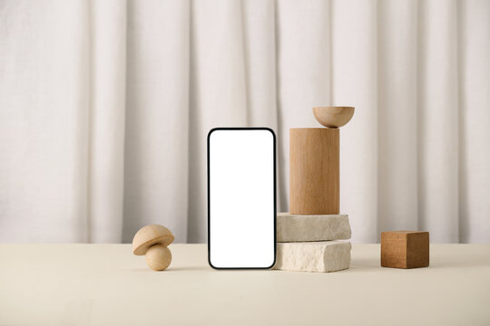 A modern phone mockup with wooden props on a minimalist table
