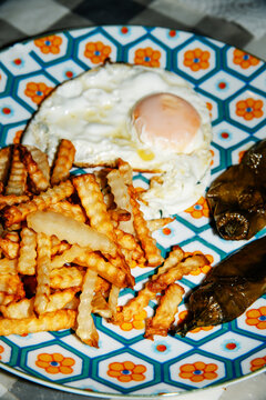close-up of fried potatoes and a fried egg on a patterned plate