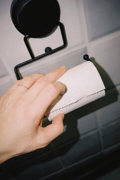 Hand finding empty toilet paper roll in bathroom