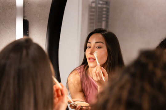 Woman applying makeup in front of a mirror