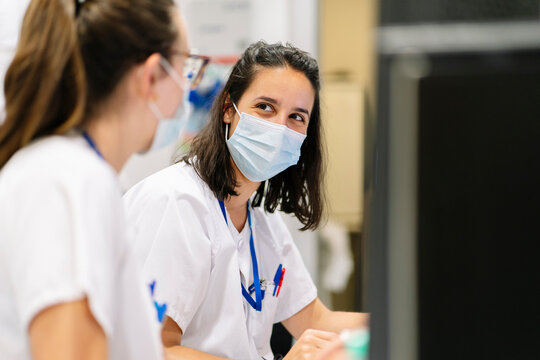 Healthcare workers wearing masks discussing at pharmacy department
