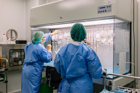 Pharmacists preparing IV medications in sterile pharmacy hood