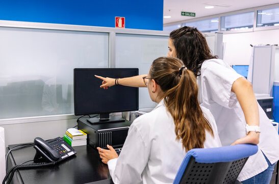 Pharmacists discussing data on a computer in a hospital pharmacy