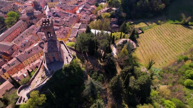 Brisighella clock tower aerial 4k spiral orbit and reveal flight in Italy. Cinematic drone pull back from Torre dell Orologio on cliff to medieval castle. Scenic hilltop village landscape scenery