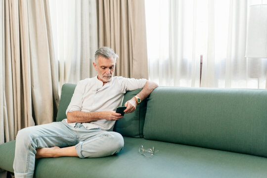 Mature man checking smartphone on hotel sofa