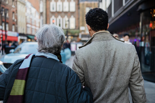 Mother and son walking arm in arm on urban street