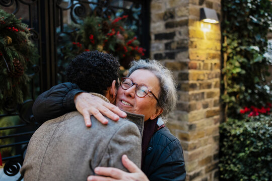 Senior woman smiling embracing younger person during christmas