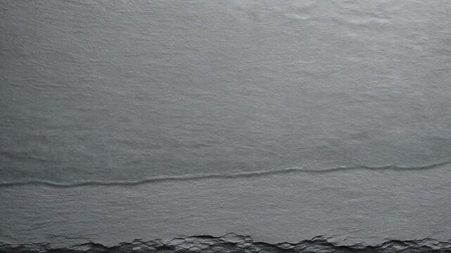 Gray slate texture with rugged edge and water surface