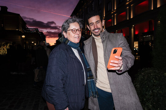 Smiling man and woman taking selfie on street at sunset