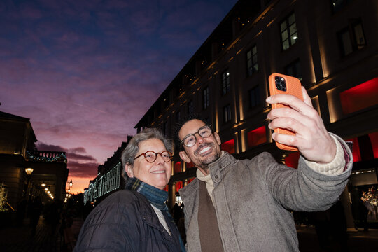 Son and mother taking selfie in London at sunset